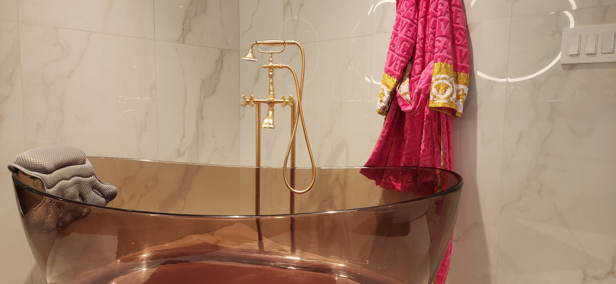Freestanding amber glass bathtub with gold tub filler