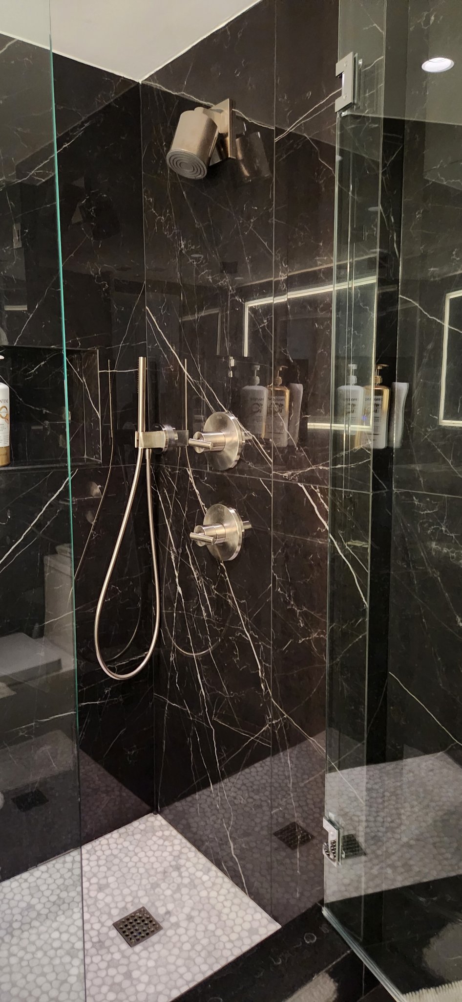 Black marble shower with frameless glass enclosure