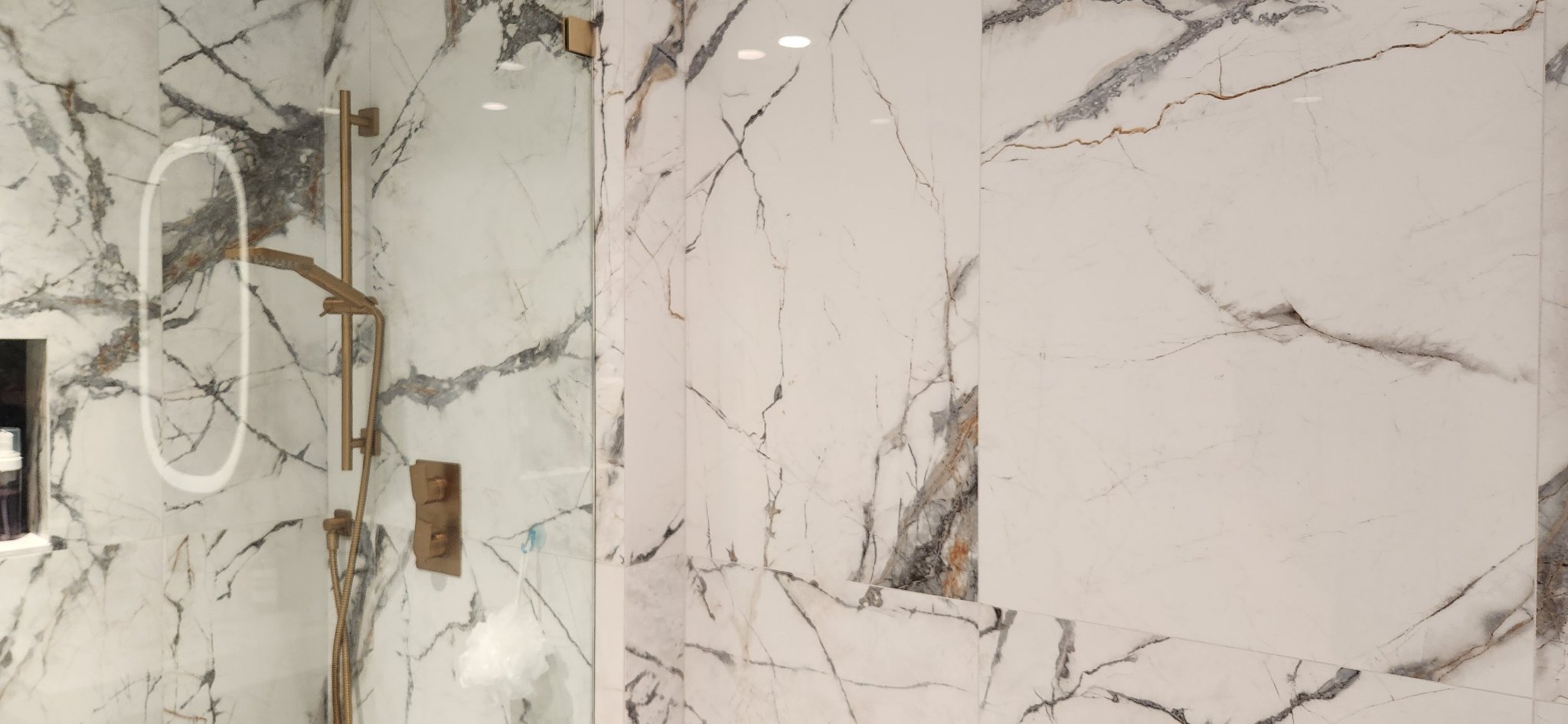 White marble shower with gold fixtures