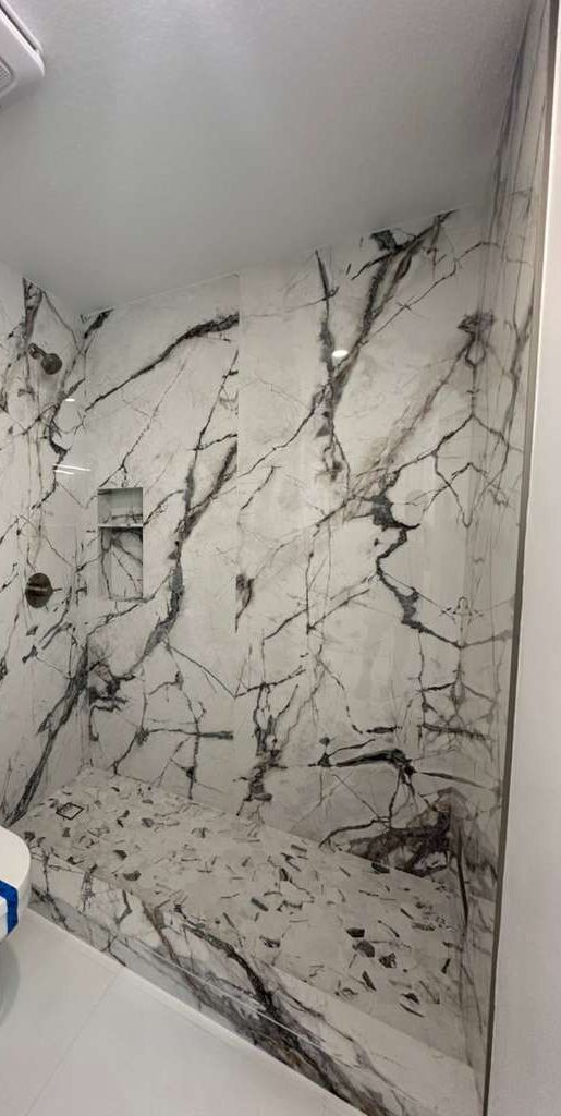 Full-height marble shower with bold veining and rain shower head