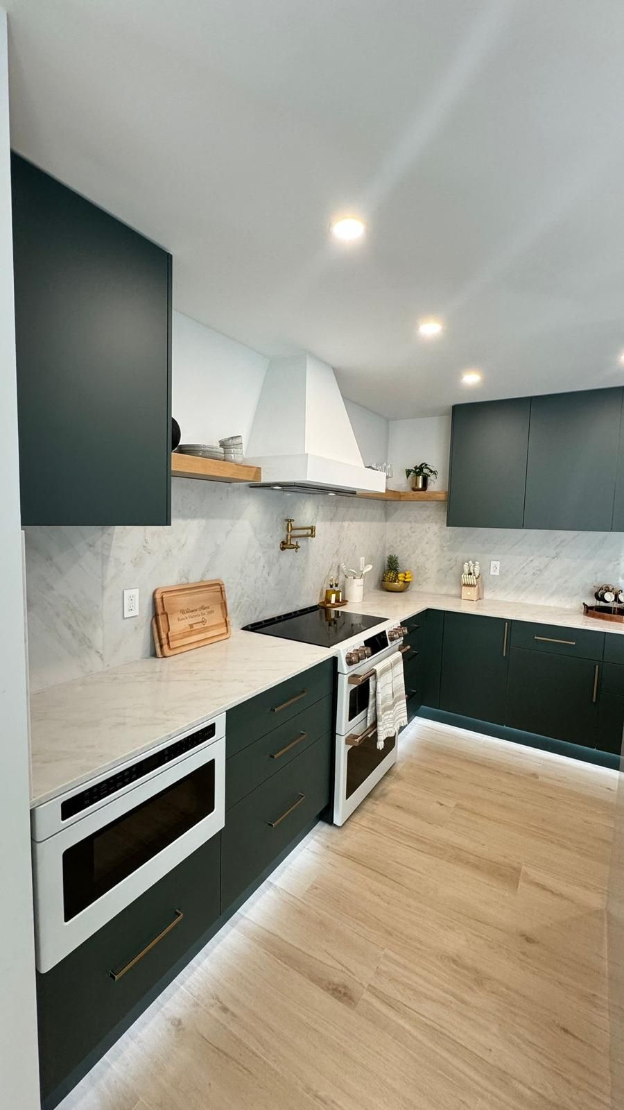 Luxury kitchen range wall with brass pot filler and open wood shelving