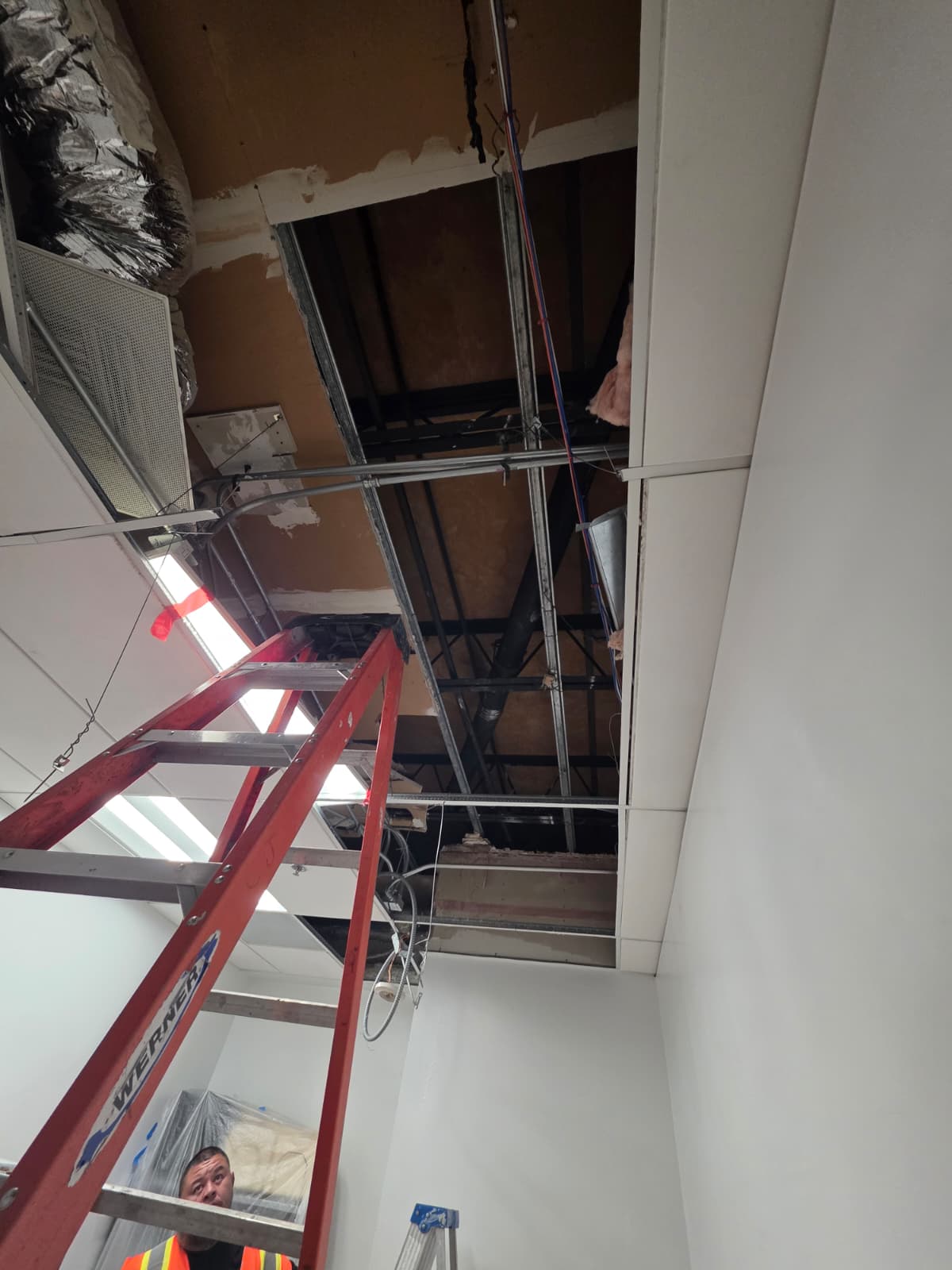 Commercial ceiling with exposed mechanical systems and HVAC ductwork during installation
